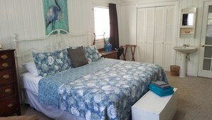 A bedroom with a bed, dresser, nightstand, and a painting of a bird. - Breathtaking Waterway Views. 1BR. 1Bath. Kitchen. Porch. 2 Person. 5 Star Views (Ocean Isle Beach)