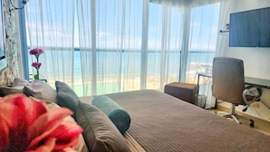 Habitación de hotel con cama, escritorio, silla y vista al océano.