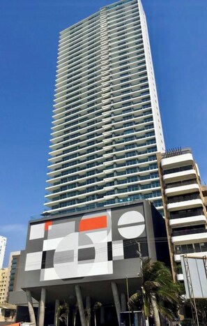 A high-rise building with a modern architectural design, featuring a series of balconies and a prominent glass facade. - Morroscity - Amazing Poolside Paradise, Ultra Fast Internet, 1BR 2Bath, 5 Stars (Cartagena)