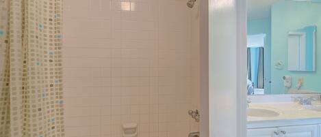 A bathroom with a shower, a sink, and a mirror.