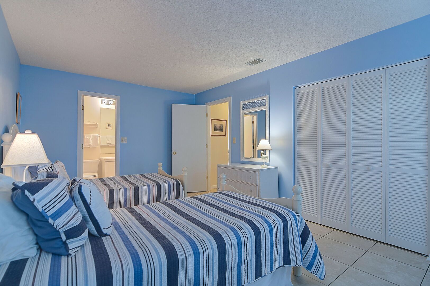 A bedroom with two beds, a dresser, a mirror, and a closet.