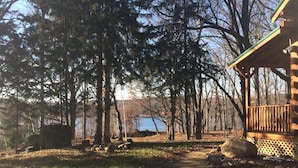 A cabin with a wooden deck, surrounded by trees and a clear sky. - Cozy Authentic Amish Cabin, 5 Acres Of Privacy, 4 Wheel Trail, Snowmobile Trail (Lampson)