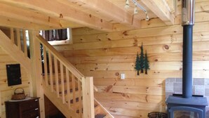 A wooden interior with a staircase, a fireplace, and a small wooden cabinet. - Cozy Authentic Amish Cabin, 5 Acres Of Privacy, 4 Wheel Trail, Snowmobile Trail (Lampson)