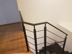 Stairs lead to a landing in a spacious room with a wooden floor.