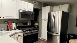 Une cuisine avec des armoires blanches, un four à micro-ondes en acier inoxydable, une cuisinière et un réfrigérateur.