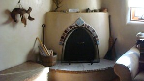 A fireplace with a stone arch, a wooden bench, and a wall-mounted shelf with various items. - Rural appeal yet so close to town (Taos)