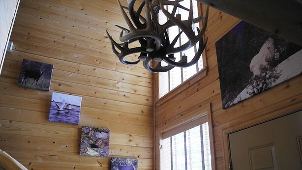 A wooden interior with a chandelier, wooden walls, and artwork. - Yellowstone Rustic Luxury Condo Sleeps 11 in an Award Winning Resort (Island Park)