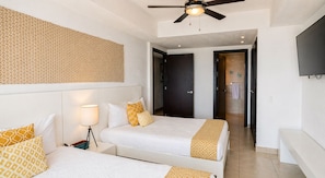 A hotel room with two beds, a ceiling fan, a TV, and a patterned wall.
