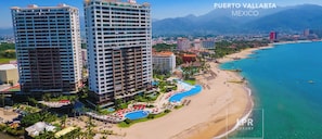 A coastal hotel with multiple high-rise buildings, a beach, and a pool area.