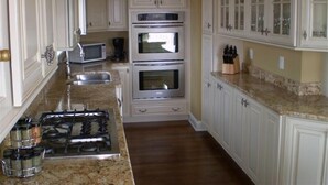 A kitchen with white cabinetry, a gas stove, a microwave, and two ovens. - Charming Chappaquiddick Retreat: Steps from Private Beach & Edgartown's Best! (Edgartown)
