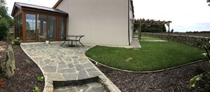 A patio with a stone floor, a table, and a lawn area. - Tullig Rock a Beautiful Country Home; Also available, Stone Cottage (Leap)