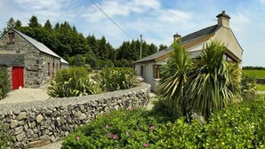 A stone building with a red door, a smaller adjacent house, and a stone wall with greenery in front. - Tullig Rock a Beautiful Country Home; Also available, Stone Cottage (Leap)
