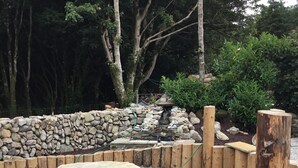 A garden with a stone wall, wooden posts, and a gravel area. - Tullig Rock a Beautiful Country Home; Also available, Stone Cottage (Leap)