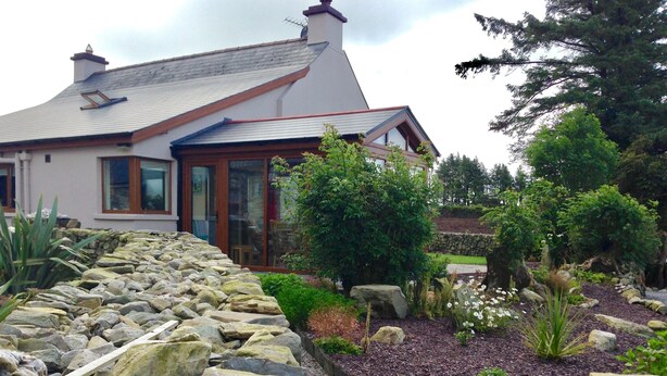 A house with a stone pathway leading to a garden with various plants and a wooden deck. - Tullig Rock a Beautiful Country Home; Also available, Stone Cottage (Leap)