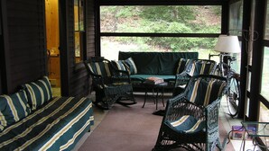 A cozy room with a sofa, two wicker chairs, a small table, and a bicycle.