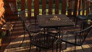 Una terraza de madera con una mesa y sillas, con vista a un lago y montañas.