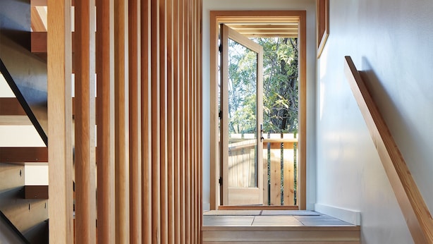 A wooden staircase with a view of a garden through a glass door. - The Horizon- Award Winning- Sauna Available for a fee (Grand Marais)