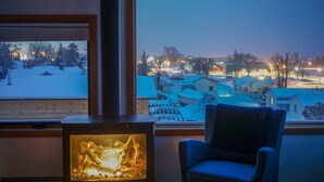 A room with a view of a snowy landscape at dusk, a fireplace, and a chair. - The Horizon- Award Winning- Sauna Available for a fee (Grand Marais)
