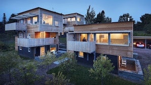 A modern multi-story house with wooden exterior and balconies, featuring large windows and a driveway. - The Horizon- Award Winning- Sauna Available for a fee (Grand Marais)