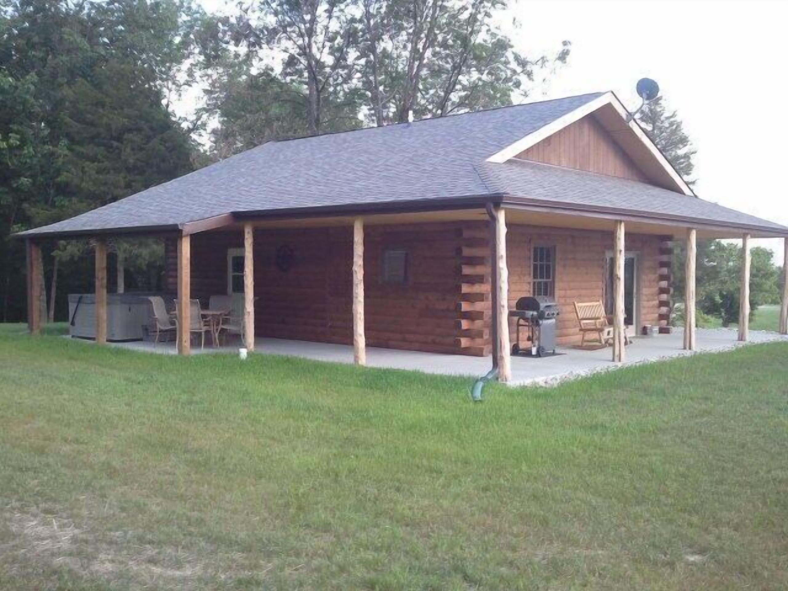 Une cabane en rondins dotée d’un porche couvert, d’un jacuzzi et d’un espace barbecue.
