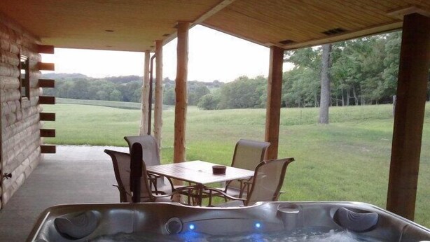 A hot tub with a view of a grassy field and trees.