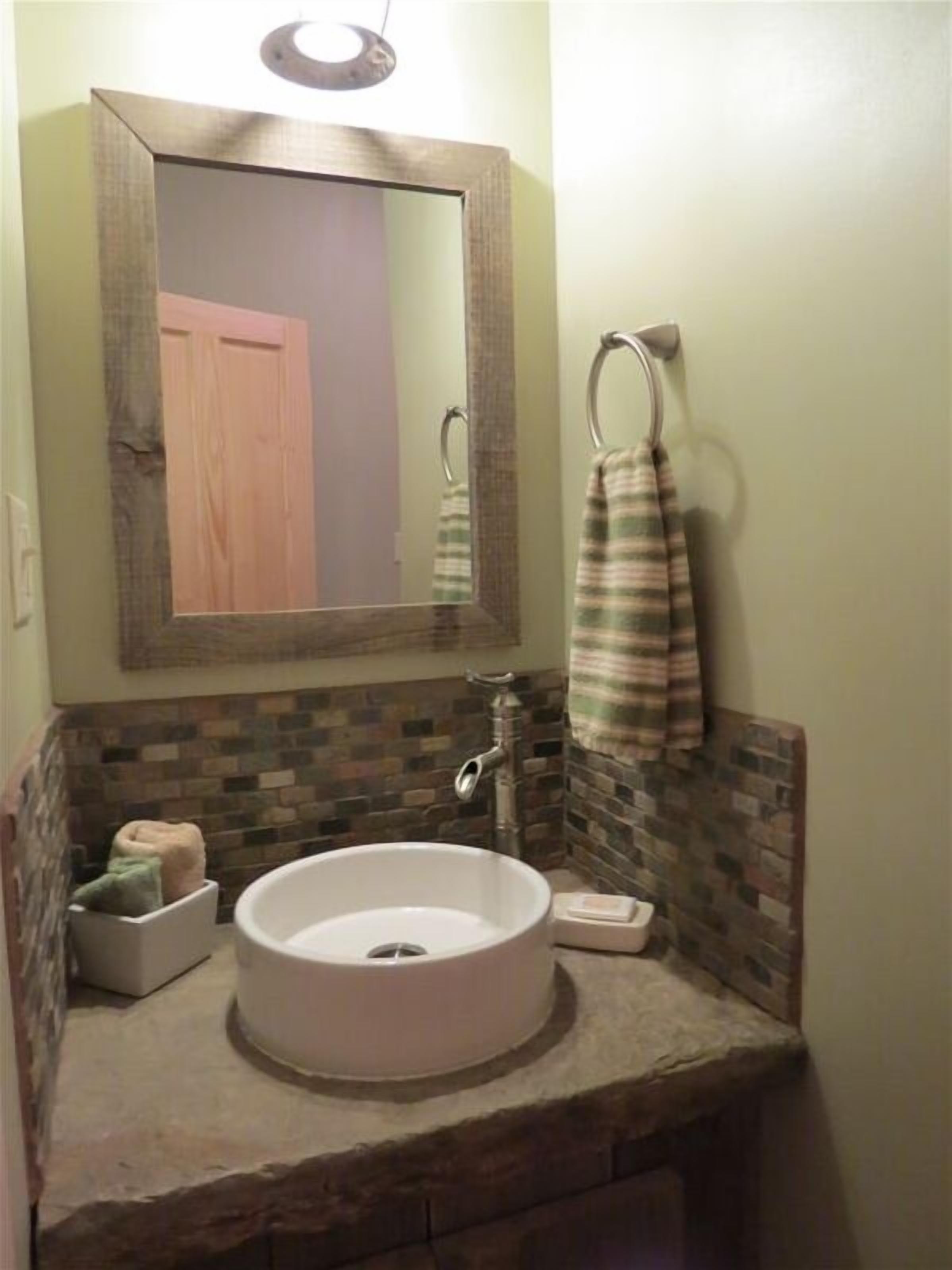 Une salle de bain avec un lavabo rond, un miroir et une serviette suspendue à un porte-serviettes.