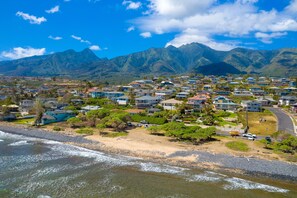 A coastal residential area with houses, a beach, and mountains in the background. - Perfect getaway for couples, honeymooners (Wailuku)