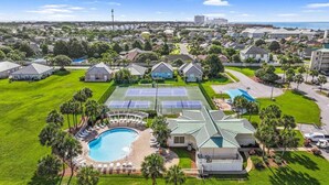 A residential area with a swimming pool, tennis courts, and a large house with a green roof. - Charming, Pet Friendly Maravilla Cottage ~ Sleeps 8 ~ Beach Service Included (Destin)