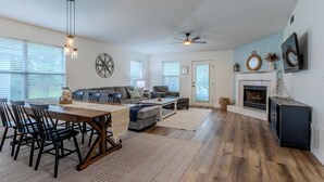 A spacious living area with a dining table, chairs, sofas, a fireplace, and a ceiling fan. - Charming, Pet Friendly Maravilla Cottage ~ Sleeps 8 ~ Beach Service Included (Destin)