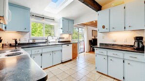 A modern kitchen with light blue cabinets, a skylight, and a large window. - A lakefront playground near beautiful Victoria on British Columbia's west coast. (victoria)