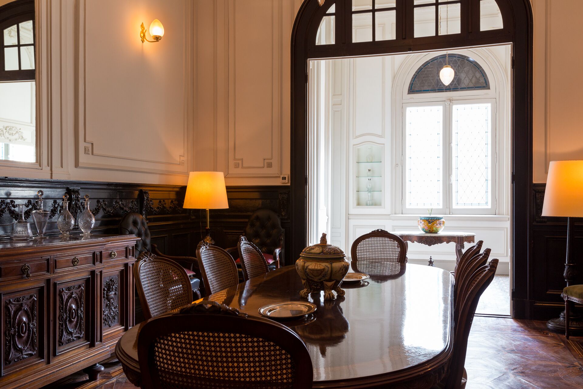Un comedor formal con una mesa grande, sillas ornamentadas y una araña.