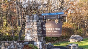 Un cartello in pietra con la scritta 'Welcome to Cacapon Resort State Park' e 'Attività e alloggi tutto l'anno'.