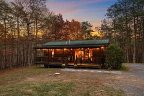 Een chalet met een veranda, omgeven door bomen.