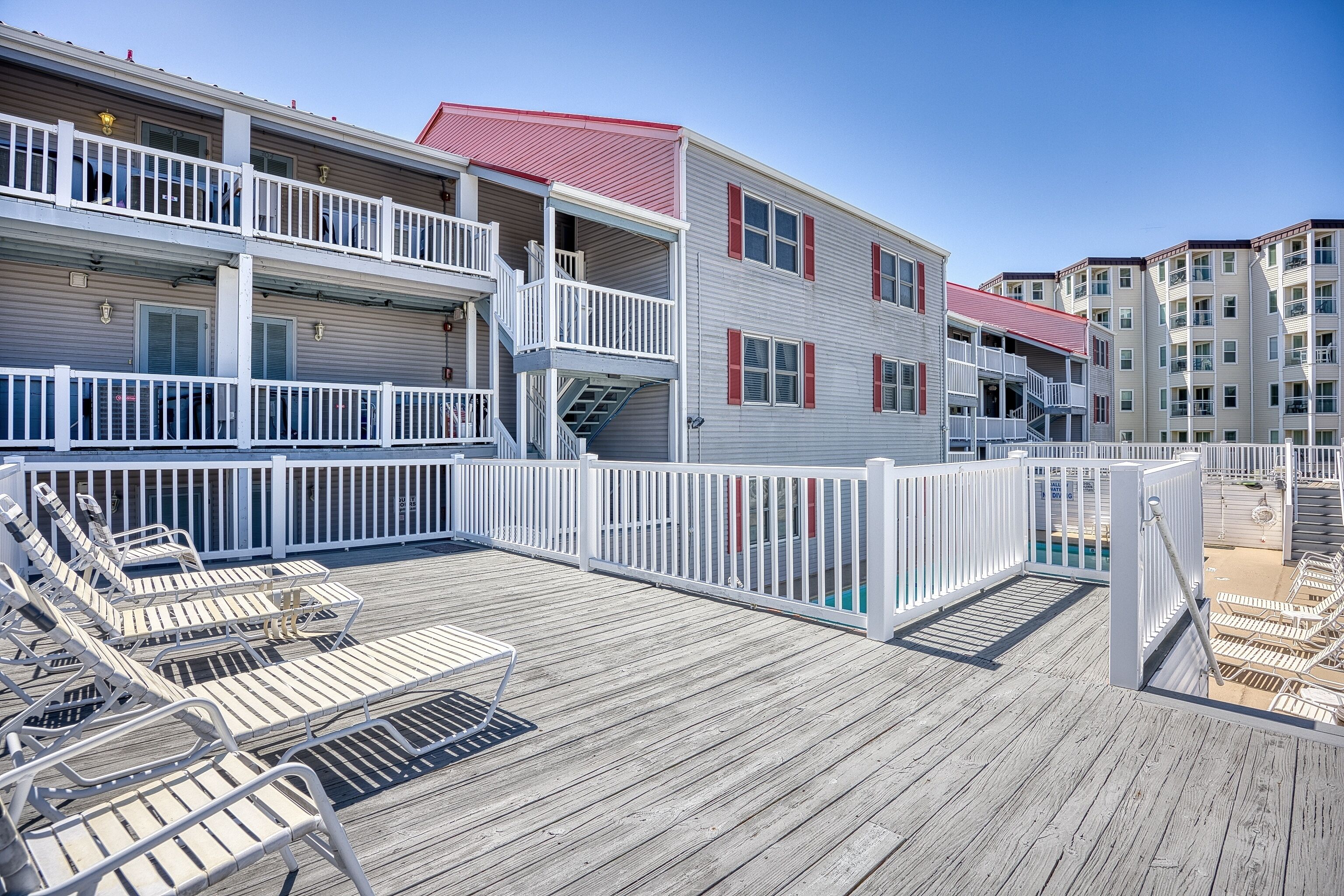 A multi-story hotel with balconies, a pool area, and lounge chairs.