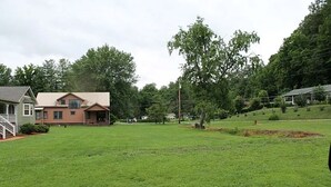Un área verde con una casa y árboles al fondo.