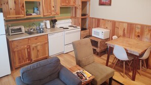 Una cocina compacta con armarios de madera, estufa, microondas y un comedor con mesa y sillas.