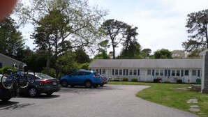 A residential street with parked cars and bicycles, a house, and a mobile home in the background. - Dennisport - Studio Condo w kitchenette  - Walk to beach  (Dennis)