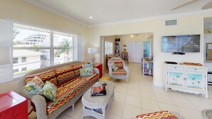 A spacious living room with a sofa, armchairs, and a television. - OCEAN FRONT, 7M BEACH, PLANTATION VILLAGE #28 (George Town)