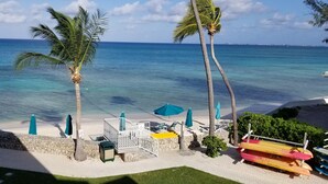 A beach view with palm trees, a lifeguard tower, and a clear blue ocean. - OCEAN FRONT, 7M BEACH, PLANTATION VILLAGE #28 (George Town)