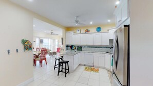 A kitchen with white cabinets, a stainless steel refrigerator, and a tiled backsplash. - OCEAN FRONT, 7M BEACH, PLANTATION VILLAGE #28 (George Town)
