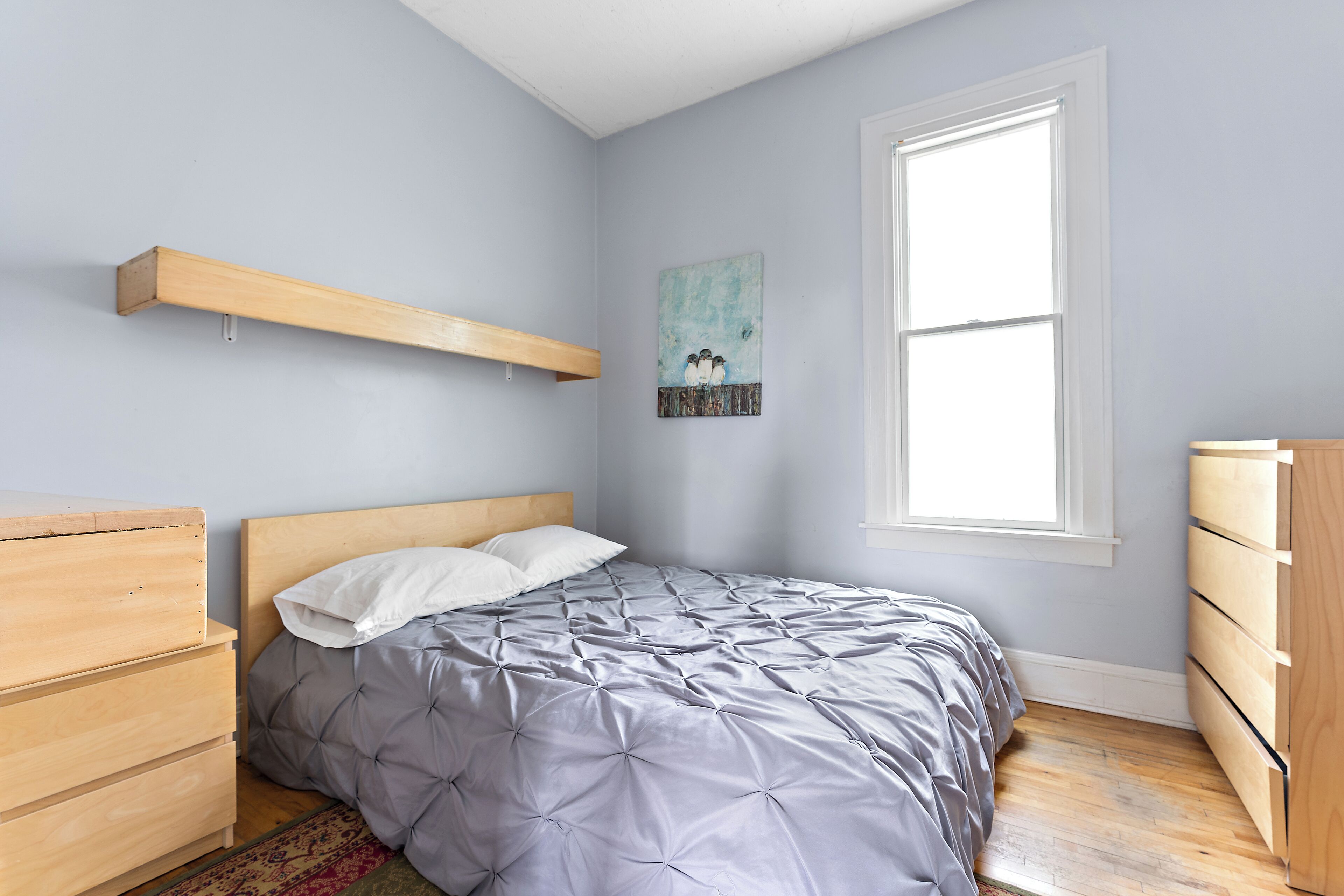 Une chambre à coucher avec un lit, une commode en bois et une fenêtre.
