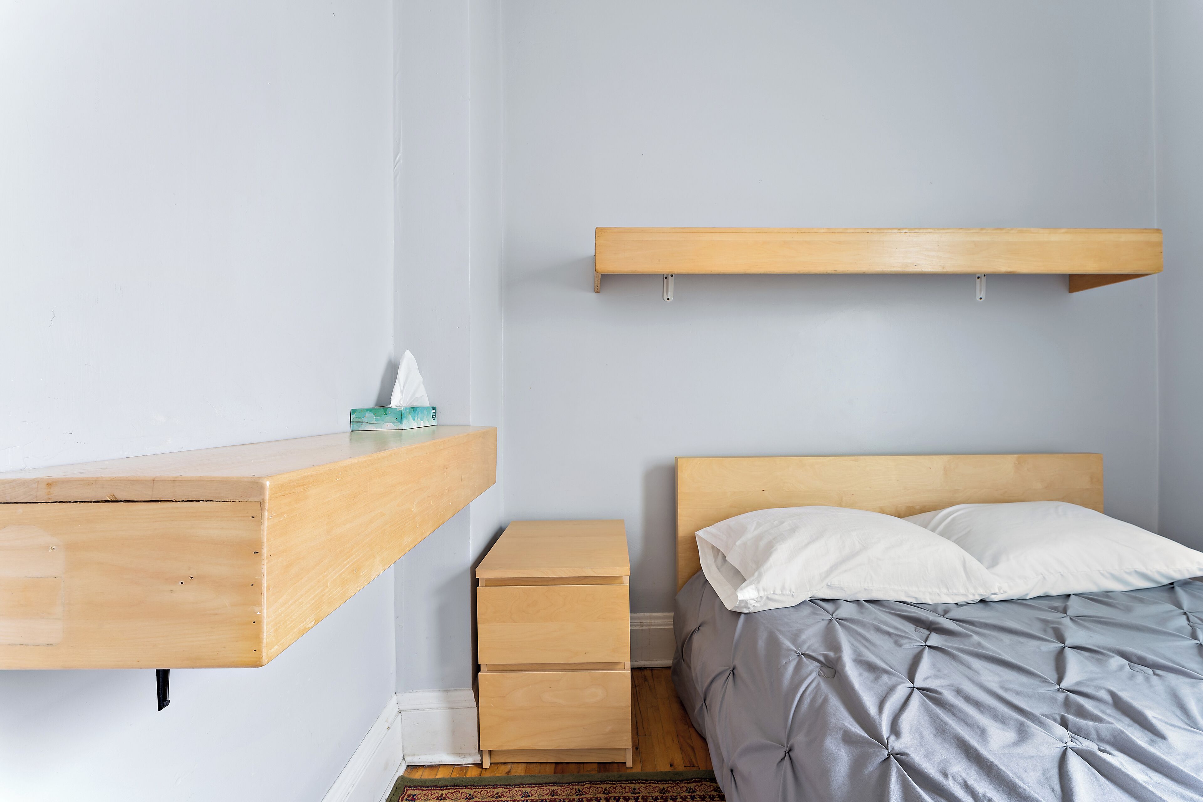 Ein Schlafzimmer mit einem Bett, einem Nachttisch, einem Holztisch und einem Regal.
