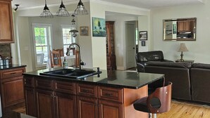A kitchen with a central island, wooden cabinets, and pendant lighting. -  the "LAKE HOUSE" - PONTOON INCLUDED (Middleville)