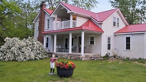 A two-story house with a red roof, a balcony, and a stone foundation. -  the "LAKE HOUSE" - PONTOON INCLUDED (Middleville)