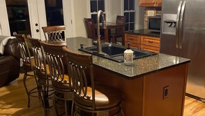 A kitchen with a central island, bar stools, a stainless steel refrigerator, and pendant lighting. -  the "LAKE HOUSE" - PONTOON INCLUDED (Middleville)