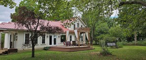 Une maison blanche avec un toit rouge, une véranda meublée et une balançoire dans le jardin.