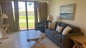 A living room with a sofa, two side tables, a coffee table, and a painting on the wall. - Beautiful Ocean Village -  On Hole One of the lower floor of the golf course (Fort Pieerce)