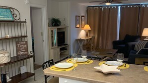 A modern kitchen with a central island, white cabinetry, and a dining area with yellow placemats. - Beautiful Ocean Village -  On Hole One of the lower floor of the golf course (Fort Pieerce)