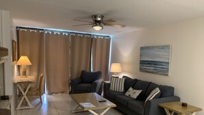 A living room with a sofa, two side tables, a coffee table, a ceiling fan, and a painting on the wall. - Beautiful Ocean Village -  On Hole One of the lower floor of the golf course (Fort Pieerce)