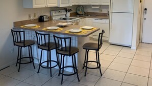 A kitchen with white cabinets, a central island with bar stools, a microwave, a refrigerator, and a dishwasher. - Beautiful Ocean Village -  On Hole One of the lower floor of the golf course (Fort Pieerce)